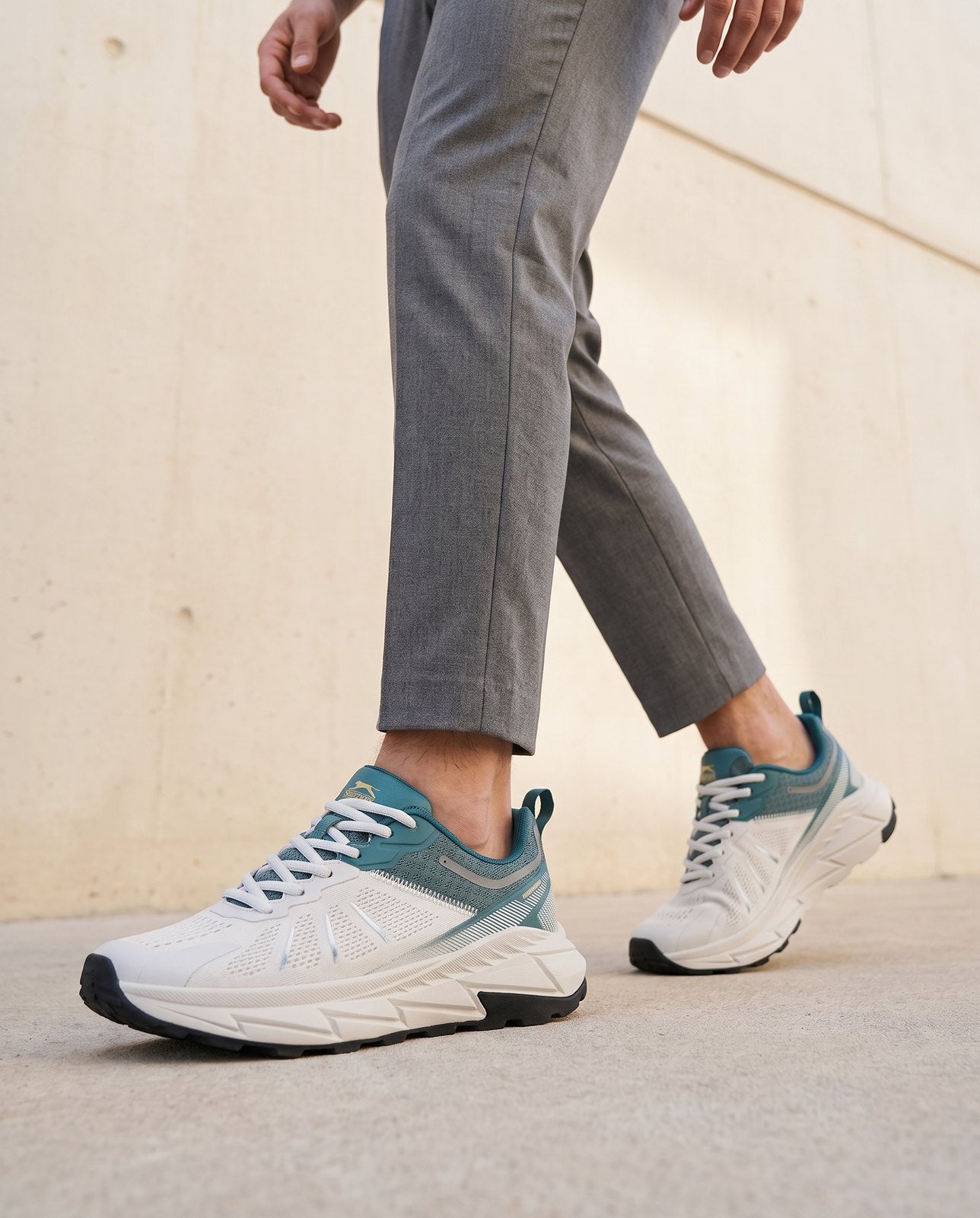 Model mid-stride in the Slazenger Warren in white and green, worn with grey trousers